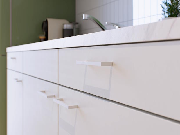 Een close-up van witte keukenkasten met moderne handgrepen en een marmeren werkblad. De keukenkasten zijn gemaakt van zonnebloempitten en rietsuiker.